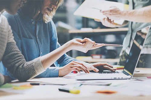 Las personas que trabajan juntas en las computadoras portátiles