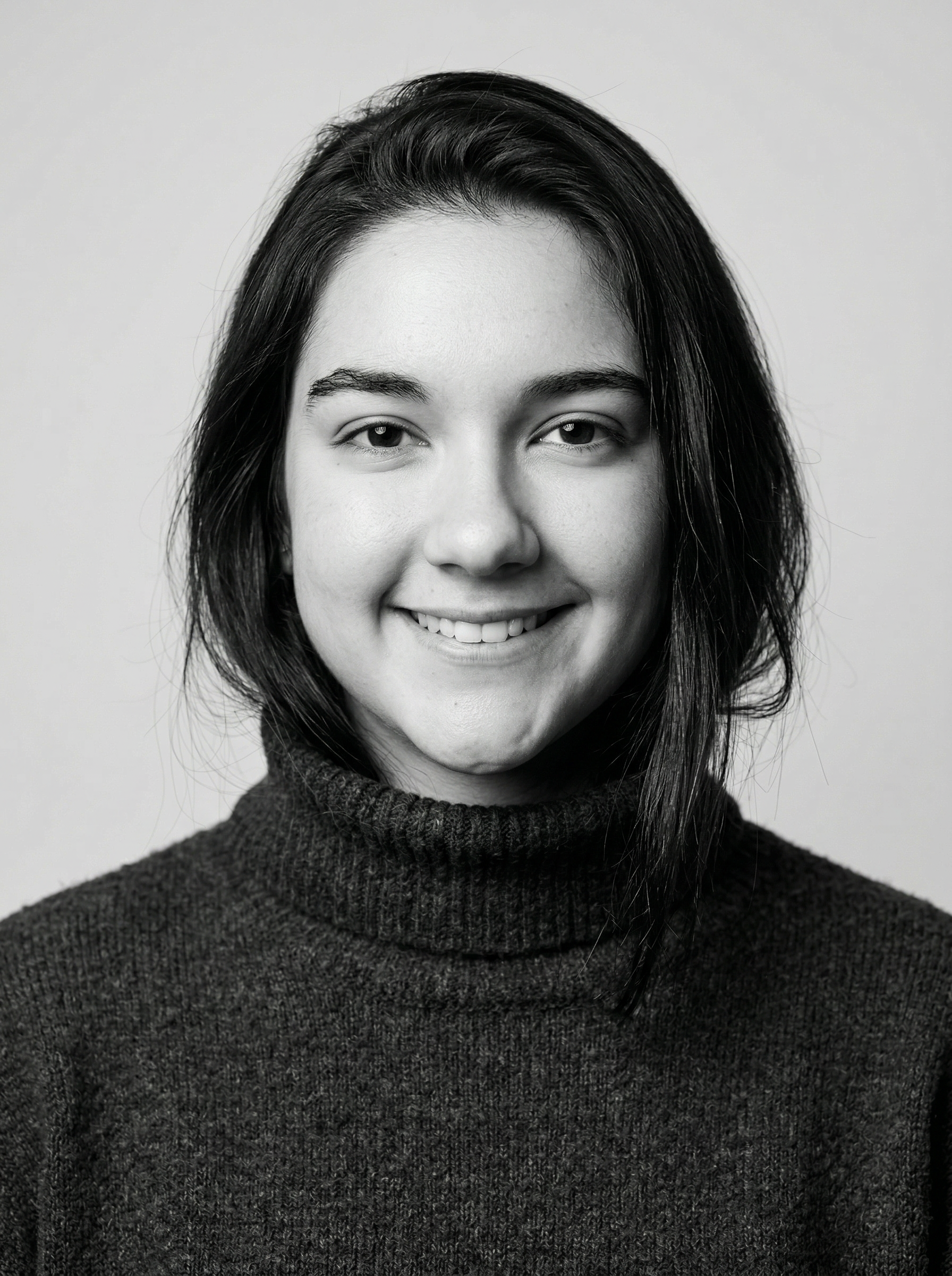 Smiling woman with long dark hair wearing a turtleneck sweater.