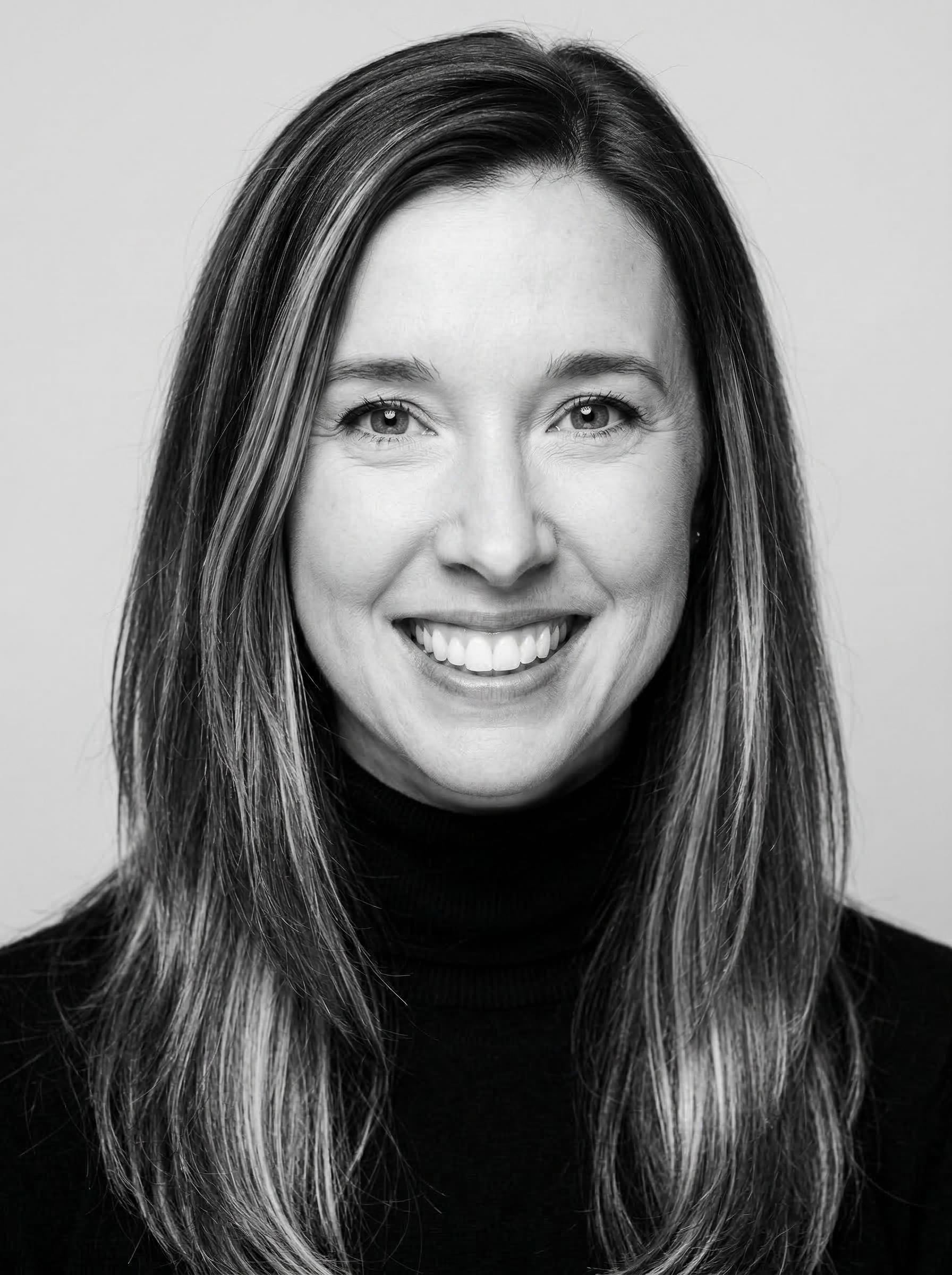 Black and white portrait of a smiling woman with long hair.